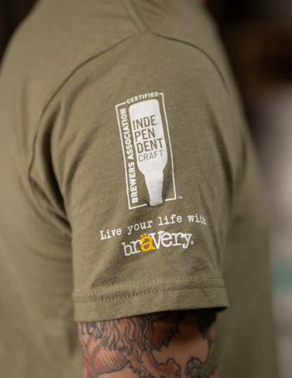 seal of independent craft on right sleeve of green t-shirt, "live your life with Bravery" written below