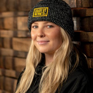 Woman in dark grey beanie with yellow and black Bravery Brewing patch