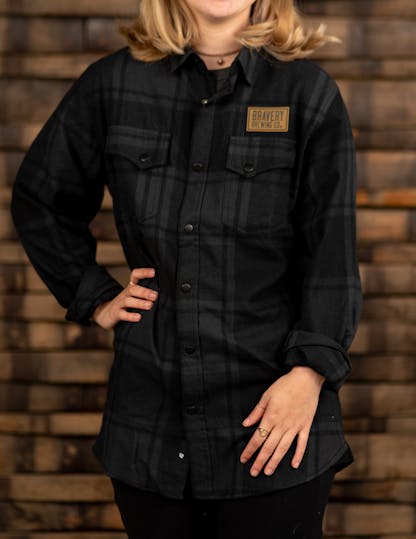 Black and grey plaid flannel shirt with leather Bravery Brewing logo patch above left chest pocket
