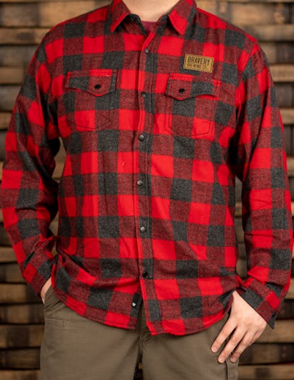 Red and black plaid flannel shirt with leather Bravery Brewing logo patch above left chest pocket