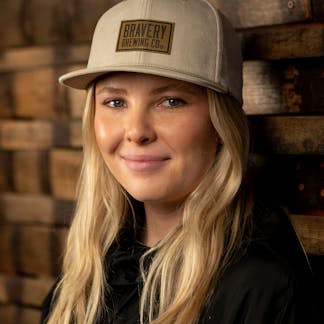 Woman in light brown corduroy hat with leather logo patch on front