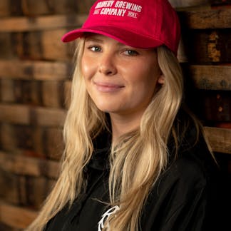 Woman in red cap with "Bravery Brewing Company" embroidered in white on front