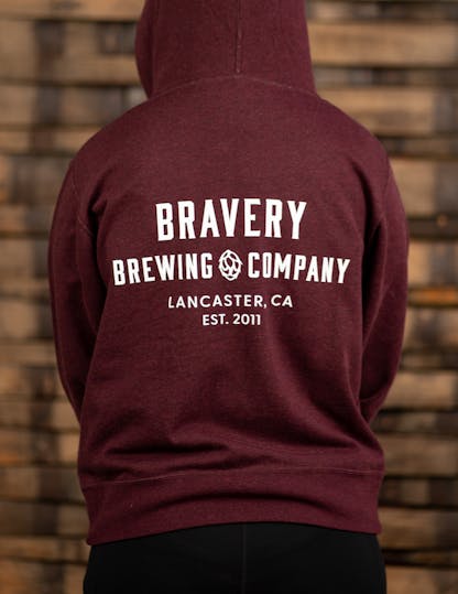 Dark red zip-up hoodie with large white text on the back reading, "Bravery Brewing Company, Lancaster CA, est. 2011"