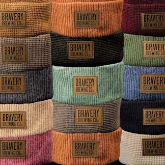 several colors of knit beanies, leather Bravery Brewing patches