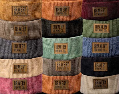 several colors of knit beanies, leather Bravery Brewing patches