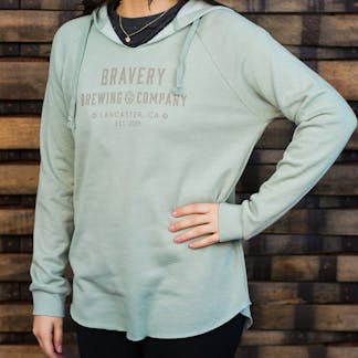 Woman in light blue sweater, "Bravery Brewing Company Lancaster, CA, est. 2011" written in grey letters