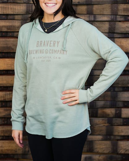 Woman in light blue sweater, "Bravery Brewing Company Lancaster, CA, est. 2011" written in grey letters