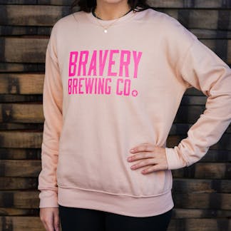 Woman in light pink sweatshirt, "Bravery Brewing" in hot pink lettering