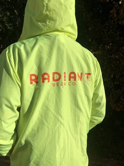 Neon yellow windbreaker jacket with Radiant Beer Co. Logo in orange