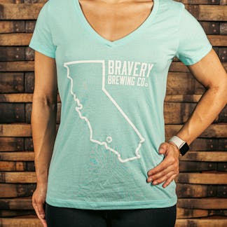 front of a light blue women's V-Neck style t-shirt. There is a large outline of the state of California with a star near the bottom of the state where Bravery is located. Next to the outline of the state is the text "Bravery Brewing Co." Both the illustration and text are printed in white ink.
