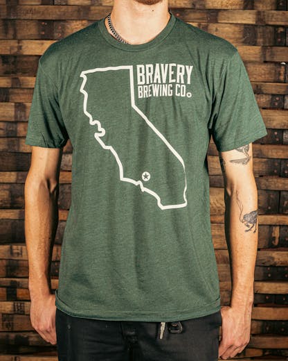 front of a green t-shirt. There is a large outline of the state of California with a star near the bottom of the state where Bravery is located. Next to the outline of the state is the text "Bravery Brewing Co." Both the illustration and text are printed in white ink.