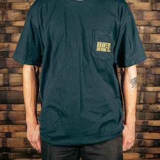 front of a navy t-shirt with a pocket on the wearer's left. printed on the pocked is the text "Bravery Brewing Co." in yellow ink.