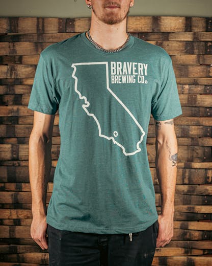 front of a teal heather t-shirt. There is a large outline of the state of California with a star near the bottom of the state where Bravery is located. Next to the outline of the state is the text "Bravery Brewing Co." Both the illustration and text are printed in white ink.