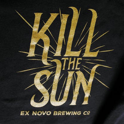 close up of shiny gold logo on black sweatshirt with large text "Kill the Sun" and smaller horizontal text beneath "Ex Novo Brewing Co"