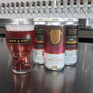 Lady Marmalade craft seltzer 4-pack of cans and filled Craft Master Grand glass with tap handles in background