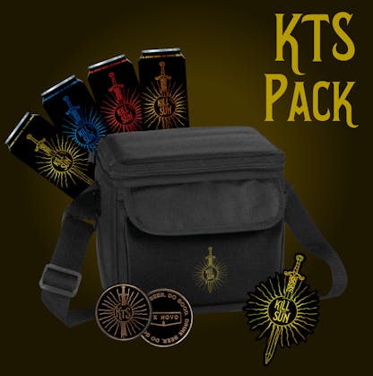 black cooler bag with long strap and custom gold embroidered sword and sun symbol on front. bright gold text at top right "KTS Pack" four 16oz black cans with various color sword and sun symbol graphics with "Kill the Sun" on each. foreground shows two black coins with gold accent text "Drink Beer Do Good" and "KTS" and "Ex Novo". right front shows sticker of gold sword and sun symbol "Kill the Sun"