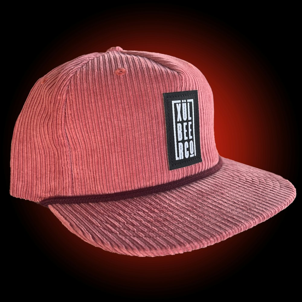 salmon colored pinch front 5 panel grandpa hat with black logo patch with burgundy rope