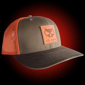 Olive and orange trucker hat with leather fanghead patch on the front