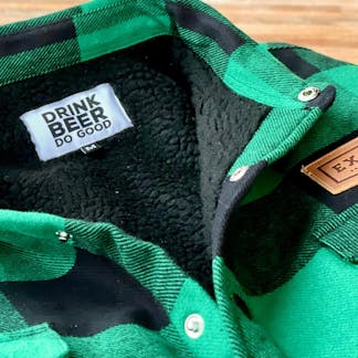 close crop collar area of green and black plaid jacket with snap closures, black sherpa lining, and faux leather front pocket patch text "Ex" interior tiny size "M" tag and larger custom tag text "Drink Beer Do Good"