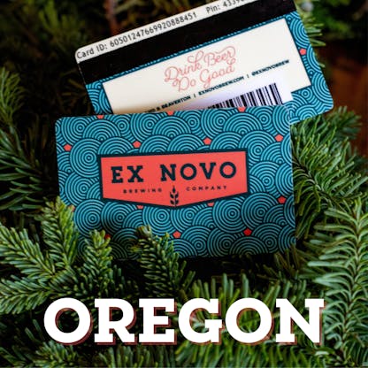 two gift cards nestled amidst evergreen boughs, front features red chevron logo with black outline text "Ex Novo Brewing Company" and repetitive design of swirl concentric circles in black with red dots interspersed. in back is reverse side of gift card with partial glimpse of bar code, black swipe stripe, yellow box with text "Drink Beer Do Good" and along top text "Card ID" followed by 16 digits and out of focus text "Pin" with illegible numbers following; white overlay text at base of image "Oregon"