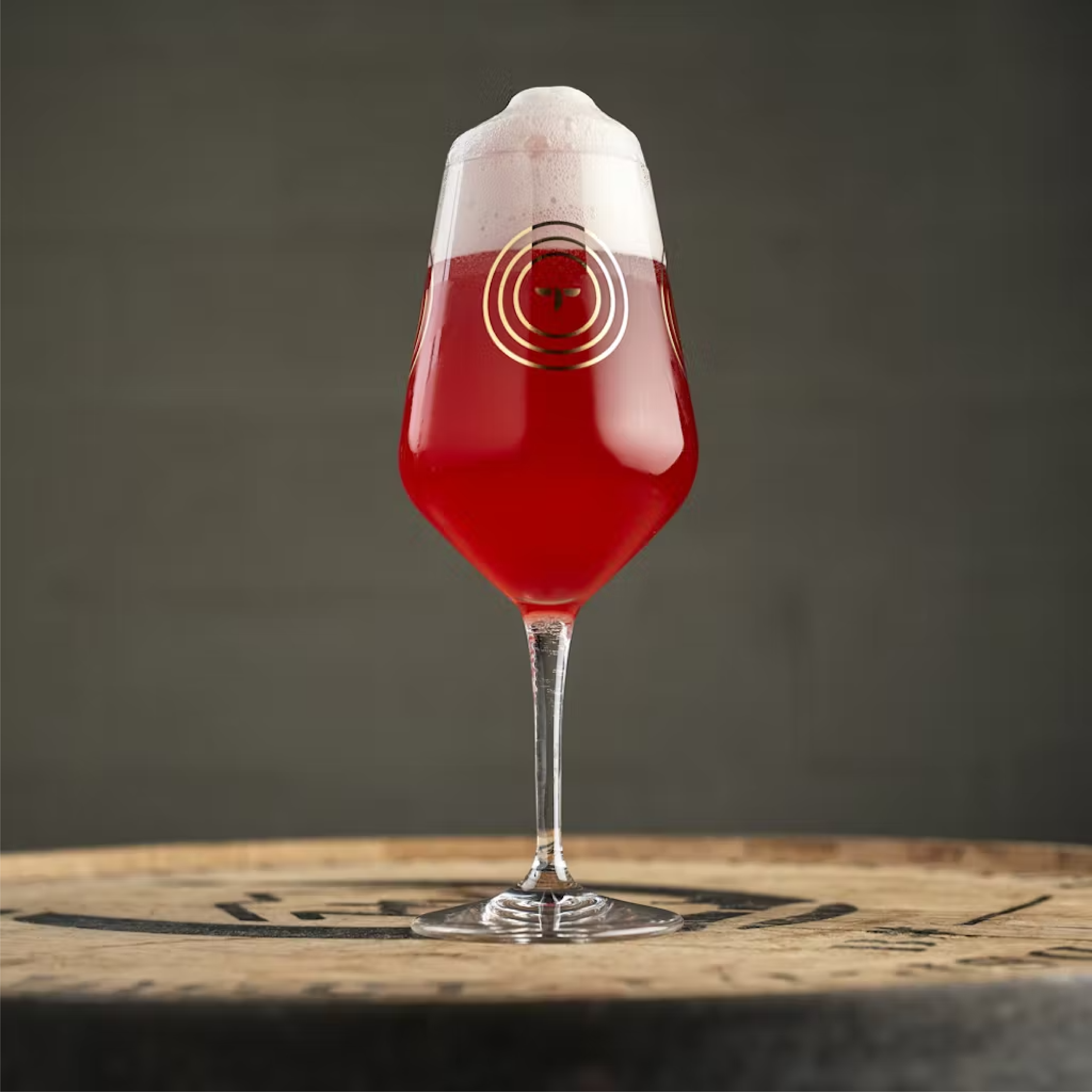red beer in wine stem glass on top of barrel