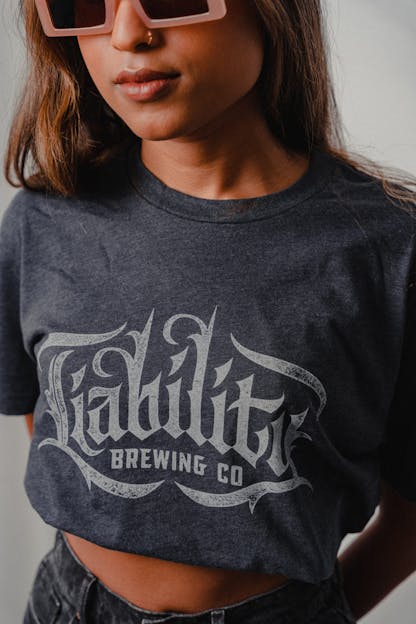 woman wearing charcoal shirt with Liability Brewing