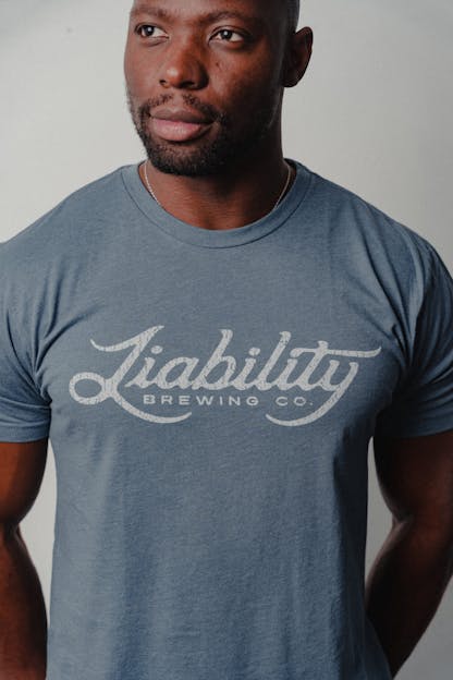 man wearing an indigo shirt with Liability Brewing