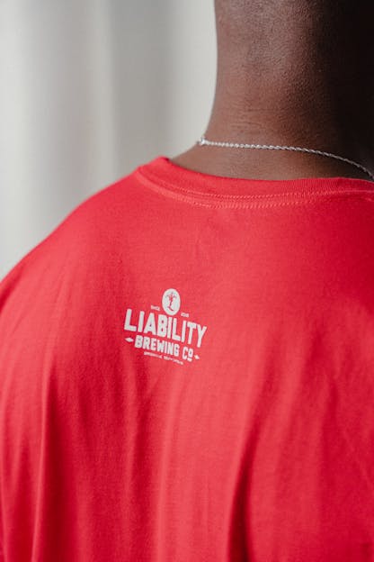 man wearing red shirt with Liability Brewing logo