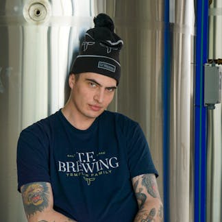 Male wearing a navy t-shirt with full print T.F.Brewing logo shirt. With Salt Lake copy.