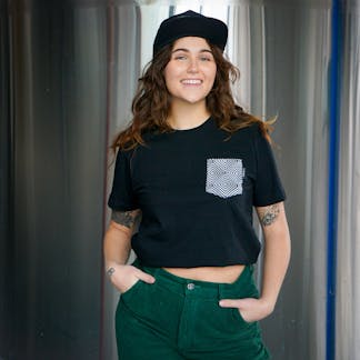 Female with a beautiful smile wearing a black t-shirt with a beer label graphic pocket design on the upper left chest. The design is of black and white diamond and square line work. It's almost hypnotizing. So is the Jesse Delmar Imperial Pastry stout.