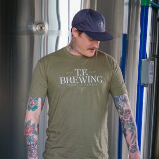 Male wearing olive color t-shirt with full T.F. Brewing logo copy on center chest