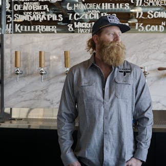 Male wearing a light gray long sleeve flannel in a taproom.