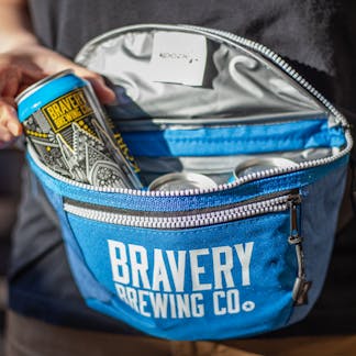 Bravery brewing Fanny Pack Cooler blue, photo has a hand pulling a can of Köbi out of the fanny pack.