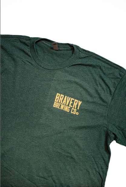 front of a dark green heather McMurphy's t-shirt. On the wearer's left chest is the text "Bravery Brewing Co." printed in yellow