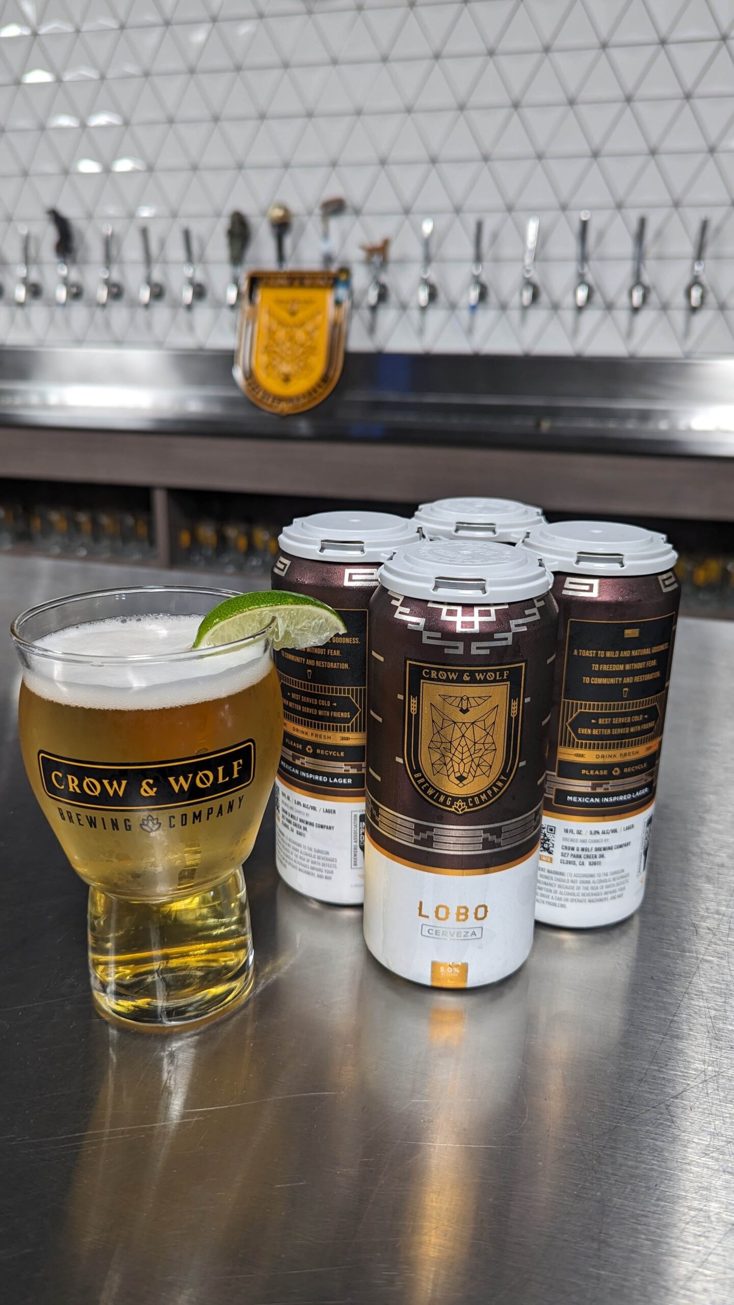 Lobo 4 pack with a pint of lobo to the left with a lime wedge on the rim