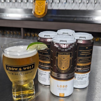 Lobo 4 pack with a pint of lobo to the left with a lime wedge on the rim
