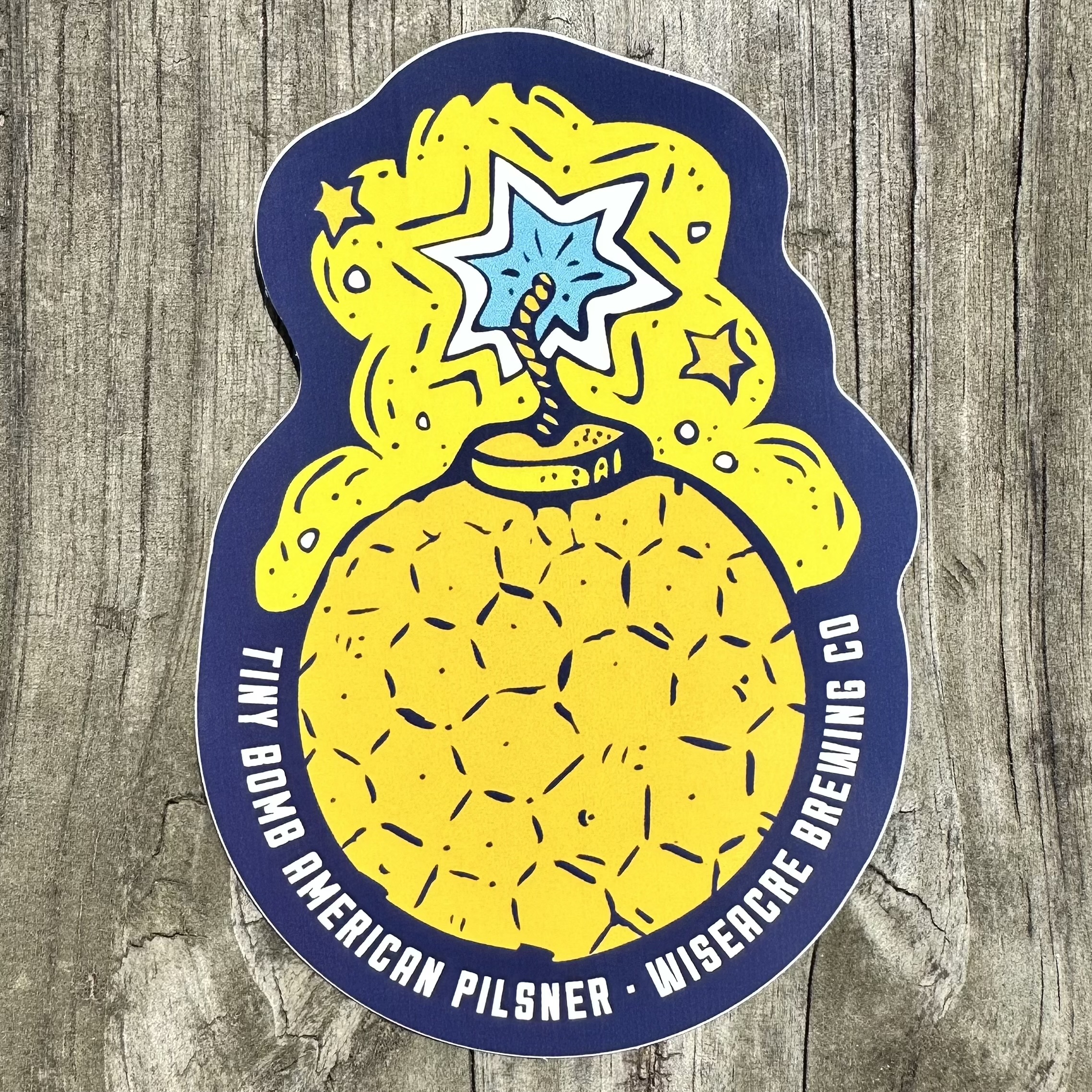 Navy and yellow sticker with Tiny Bomb beer art surrounded by text "TINY BOMB AMERICAN PILSNER WISEACRE BREWING CO"