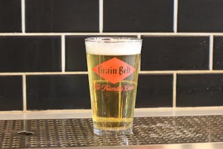 A glass of Schells beer in a glass with their logo on it 