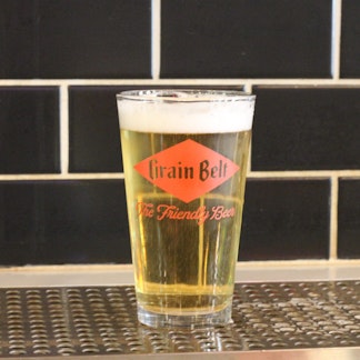 A glass of Schells beer in a glass with their logo on it