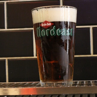 A glass of Schells beer in a glass with their logo on it