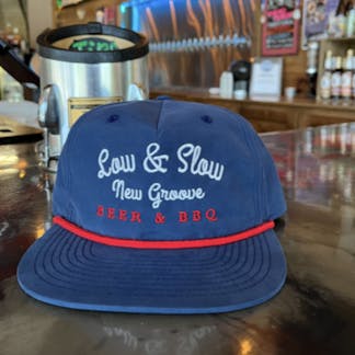 A and red hat sitting on the bar that says low and SLOW New groove beer and bbq