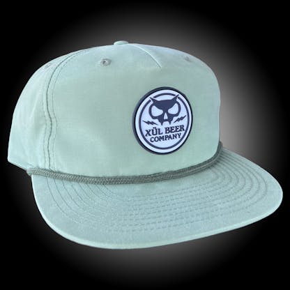 mint green grandpa hat with an olive cord across the bill and a white rubber patch with black Xul name and logo
