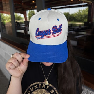 White Cap, Blue Bill, Cougar Bait written on front in blue letters.