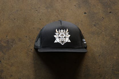 A black "trucker-style" hat. The front of the hat has the Sideward logo which resembles a many horned demon cow skull with a triangle and circle behind it.