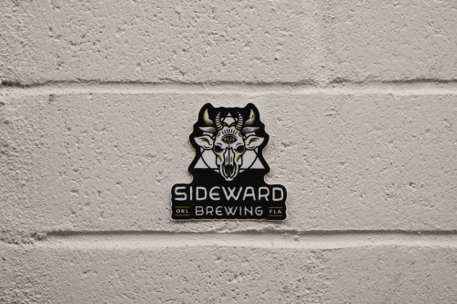 a sticker of Sideward Brewing's logo, which resembles a demon cow skull with a triangle and circle behind it, with the Sideward Brewing wordmark below.
