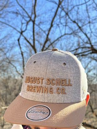 Grey, white and brown baseball hat with Schell embroidered on front.