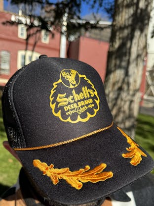 Black baseball hat with gold leaf accents and Schell logo on front.