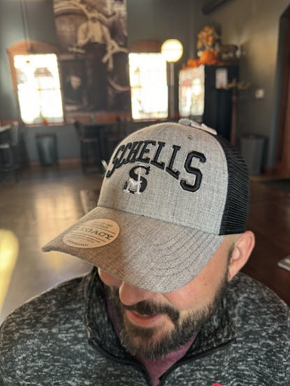 Grey and black baseball cap that says Schells