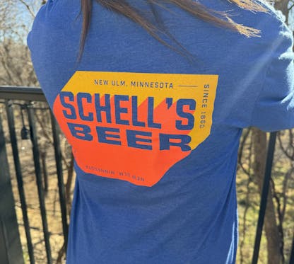 Blue long sleeve with orange and yellow Schell logo on front and back.