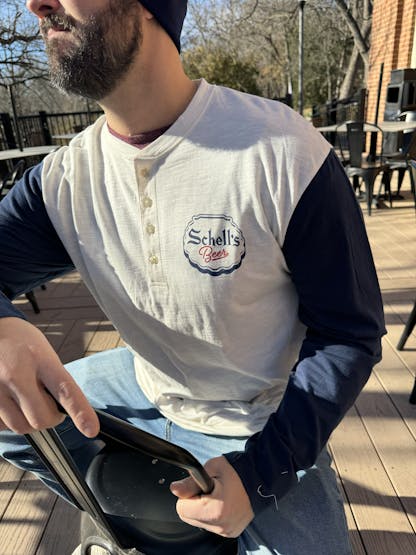 White and blue long sleeve henley with Schell logo on front.
